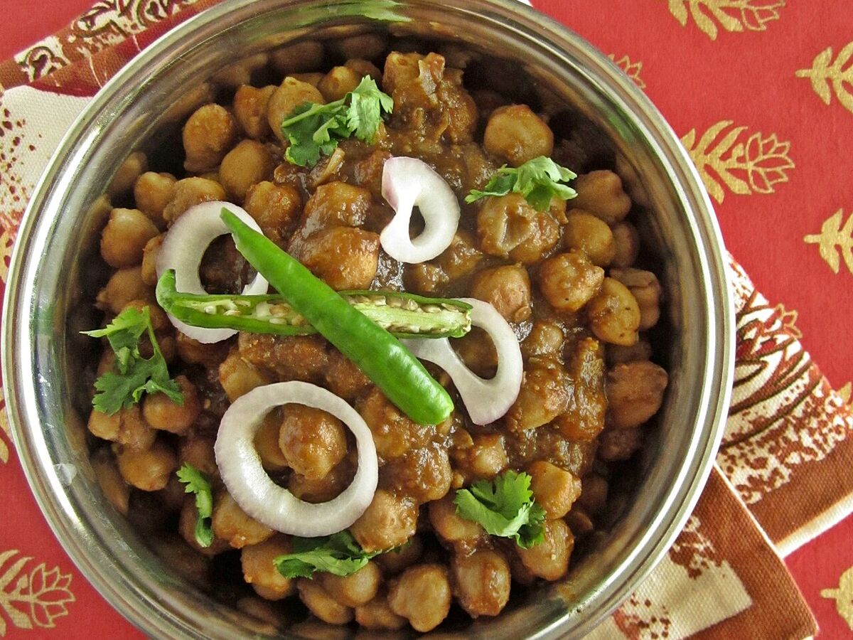 Chole masala, a chickpea curry, garnished with onion, chilli and coriander.